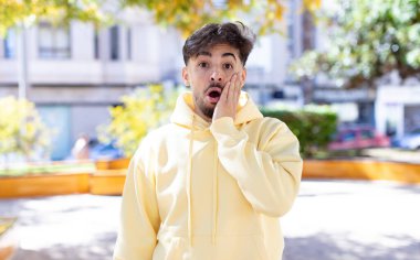 Genç yakışıklı adam şok olmuş ve ağzı açık halde yüz yüze inanamamaktan şaşkına dönmüş durumda.
