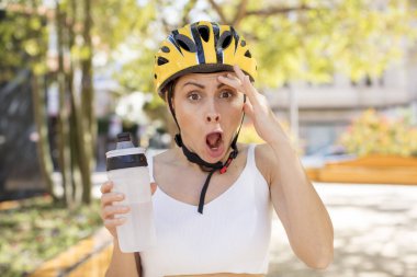 Genç ve güzel bir kadın mutlu, şaşkın ve şaşırmış görünüyor. bisiklet kaskı konsepti