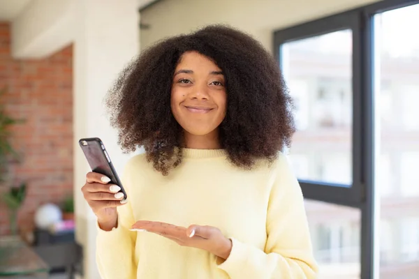 かわいいアフロ 黒人女性 陽気で微笑み 幸せを感じ コンセプトを示しています スマートフォンコンセプト — ストック写真