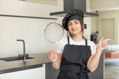 Neşeli bir şekilde gülümseyen, mutlu hisseden ve bir tarafı işaret eden genç bir kadın. Şef konsepti