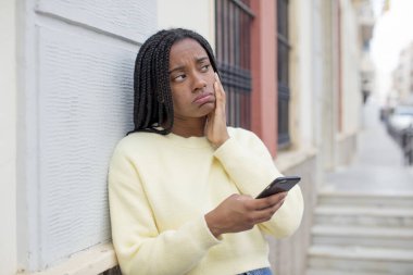 Siyah afro kadın bıkkın, yorgun ve uykulu hissediyor. akıllı telefon konseptini kullanarak