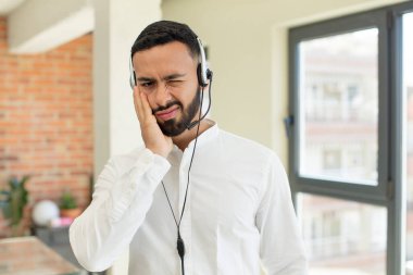 Genç yetişkin bir adam bıkkın, hayal kırıklığına uğramış ve yorucu bir günün ardından uykulu hissediyor. tele pazarlamacı kavramı