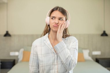 Genç ve güzel bir kadın sıkıcı, bıkkın ve uykulu hissediyor. kulaklık konsepti
