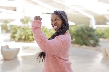 Afro güzel siyah kadın mutlu, tatmin olmuş ve güçlü hissediyor, kaslı ve formda, spor salonundan sonra güçlü görünüyor.