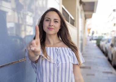 Güzel bir kadın gururla gülümsüyor ve gururla bir numaralı pozunu veriyor, kendini lider gibi hissediyor.