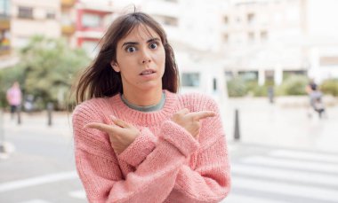 Şaşkın, kafası karışmış, güvensiz ve şüpheyle zıt yönlere bakan güzel genç bir kadın.