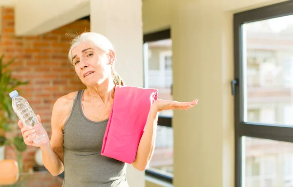 senior pretty woman shrugging, feeling confused and uncertain. fitness concept