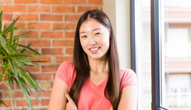 asian pretty woman at home against brick wall with a plant