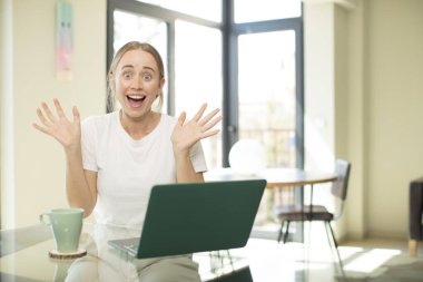 Dizüstü bilgisayarı olan beyaz, güzel bir kadın mutlu ve heyecanlı görünüyor. Beklenmedik bir sürprizle şoke oldu.