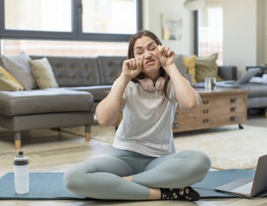 Yoga yapan genç bir kadın umutsuz ve hayal kırıklığına uğramış görünüyor, stresli, mutsuz ve sinirli, bağırıyor ve çığlık atıyor.