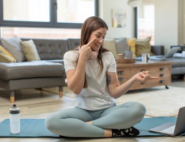 Yoga yapan genç bir kadın bir şeye göz kulak oluyor, izliyor, tetikte ve tetikte bekliyor.