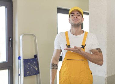 Genç yakışıklı adam neşeyle gülümsüyor, mutlu hissediyor ve bir konsept gösteriyor. Becerikli adam kavramı