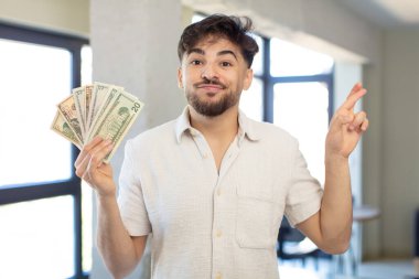 Genç yakışıklı adam şans diliyor ve şans diliyor. Dolar banknotları konsepti