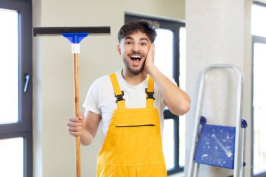 Genç yakışıklı adam kendini mutlu hissediyor ve inanılmaz bir şeye hayret ediyor. pencere temizleme konsepti