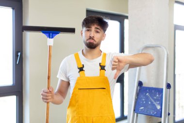 Genç ve yakışıklı bir adam kendini kötü hissediyor, baş parmağını kaldırıyor. pencere temizleme konsepti