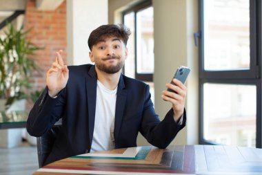 Genç yakışıklı adam şans diliyor ve şans diliyor. akıllı telefon kavramı