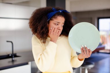Oldukça afro siyahi bir kadın korkmuş, endişeli ya da kızgın hissediyor ve yan tarafa bakıyor. ev aşçısı konsepti