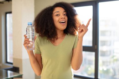 Güzel afro siyah kadın bir fikri fark ettikten sonra mutlu ve heyecanlı bir dahi gibi hissediyor. su şişesi kavramı