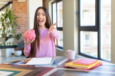 Mutlu bir şekilde gülümsemek ve bir konsept sunmak veya göstermek. Domuz kumbarası konsepti