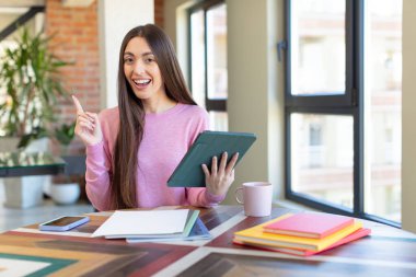 Neşeli bir şekilde gülümsüyor, mutlu hissediyor ve bir tarafı işaret ediyor. üniversite öğrencisi ve not defteri