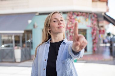 Güzel bir kadın gururla gülümsüyor ve gururla bir numaralı pozunu veriyor, kendini lider gibi hissediyor.