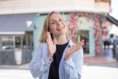 Güzel bir kadın mutlu ve başarılı hissediyor, gülümsüyor ve alkışlıyor, alkışlarla tebrik ediyor.