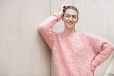 Güzel bir kadın neşeli ve sıradan bir şekilde gülümsüyor, olumlu, mutlu ve kendinden emin bir bakışla yumruk yumruğa.