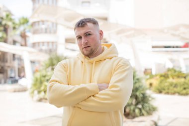 Yakışıklı adam üzgün ve hayal kırıklığına uğramış, ciddi görünüyor, sinirlenmiş ve kollarını kavuşturmuş.