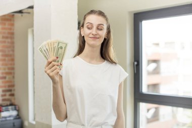 Gülümsüyor ve mutlu ve kendinden emin bir ifadeyle bakıyor. Dolar banknotları konsepti