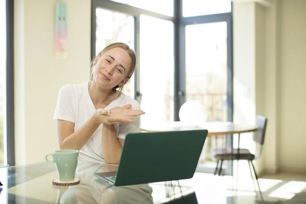 stock image caucasian pretty woman with a laptop smiling, feeling confident, successful and happy, showing concept or idea on copy space on the side