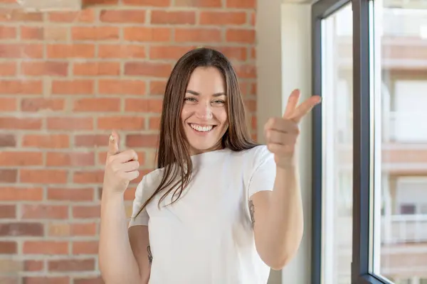 Stock image young adult pretty woman feeling happy, cool, satisfied, relaxed and successful, pointing at camera, choosing you