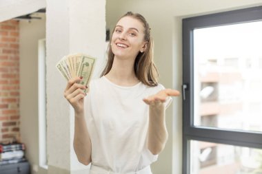 Mutlu bir şekilde gülümsemek ve bir konsept sunmak veya göstermek. Dolar banknotları konsepti