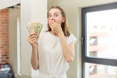 Ağzını eliyle kapatmış ve şok olmuş ya da şaşırmış bir ifade. Dolar banknotları konsepti