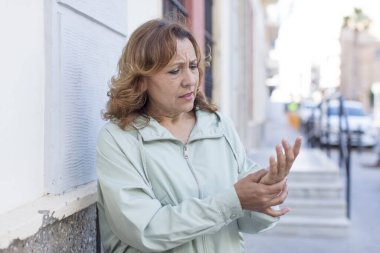 Orta yaşlı bir kadın endişeli, hasta ve mutsuz hissediyor. Acılı bir el ağrısı çekiyor.