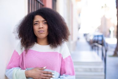 Afro-amerikan güzel bir kadın şapşal, çılgın, şaşırmış bir ifadeyle, yanakları şişmiş, doldurulmuş, şişman ve yemekle dolu