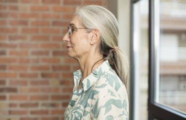 Profil görünümündeki son sınıf güzel kadın ilerideki boşluğu kopyalamak istiyor, düşünüyor, hayal ediyor ya da hayal kuruyor.