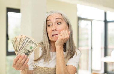 Güzel, son sınıf öğrencisi, korkmuş, endişeli ya da kızgın hisseden ve bir tarafa bakan bir kadın. Dolar banknotlarıyla