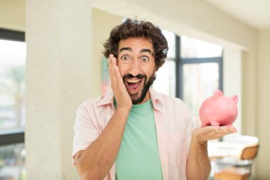 Çılgın sakallı adam inanılmaz bir şey karşısında mutlu ve şaşkın hissediyor. Domuz kumbarası konsepti