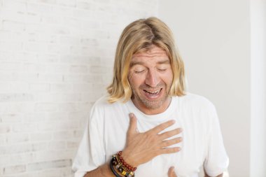 Genç sarışın yetişkin bir adam komik bir şakaya yüksek sesle gülüyor, mutlu ve neşeli hissediyor, eğleniyor.