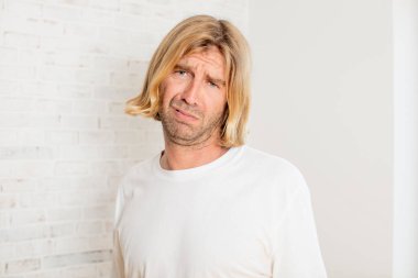 Genç sarışın yetişkin bir adam üzgün ve mızmız, mutsuz bir bakışla, olumsuz ve hayal kırıklığına uğramış bir tavırla ağlıyor.