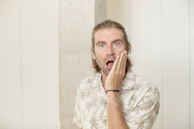 Genç sarışın yetişkin bir adam şok olmuş ve şaşkınlık içinde ağzı açık bir şekilde yüz yüze inanmamakta direniyor.