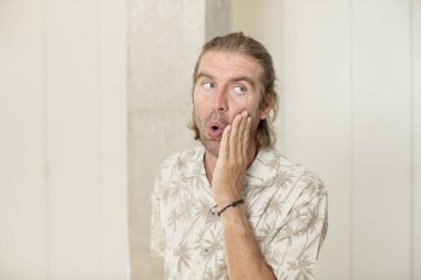 Genç sarışın yetişkin bir adam şok olmuş ve şaşkınlık içinde ağzı açık bir şekilde yüz yüze inanmamakta direniyor.