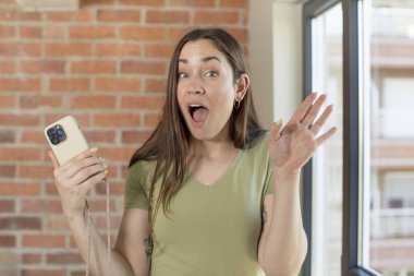 Genç ve güzel bir kadın inanılmaz bir şey karşısında kendini mutlu ve şaşkın hissediyor. akıllı telefon kavramı