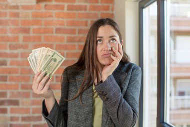 Genç ve güzel bir kadın sıkıcı, bıkkın ve uykulu hissediyor. Dolar banknotları konsepti