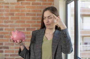 Genç, güzel bir kadın şaşırmış görünüyor, yeni bir düşünce, fikir ya da konsept fark ediyor. Domuz kumbarası konsepti