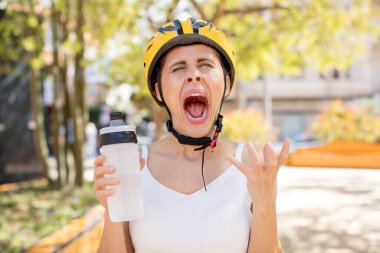 Genç ve güzel bir kadın ellerini havaya kaldırarak çığlık atıyor. bisiklet kaskı konsepti