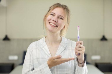 Genç, güzel bir kadın neşeyle gülümsüyor, mutlu hissediyor ve bir konsept gösteriyor. diş yıkama kavramı