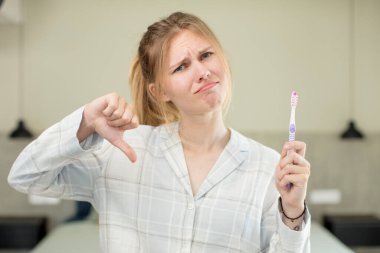 Genç ve güzel bir kadın kendini kötü hissediyor, baş parmağını kaldırıyor. diş yıkama kavramı