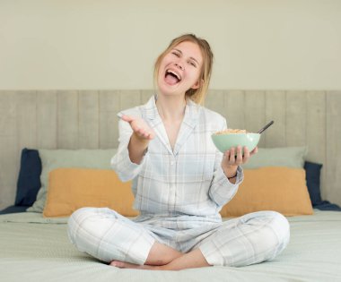 Genç ve güzel bir kadın mutlu bir şekilde gülümsüyor ve bir konsept sunuyor ya da gösteriyor. Kahvaltı kasesi konsepti