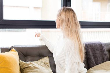 Genç, güzel bir kadın fotokopi odasında duran ve objeyi işaret eden koltukta oturan.
